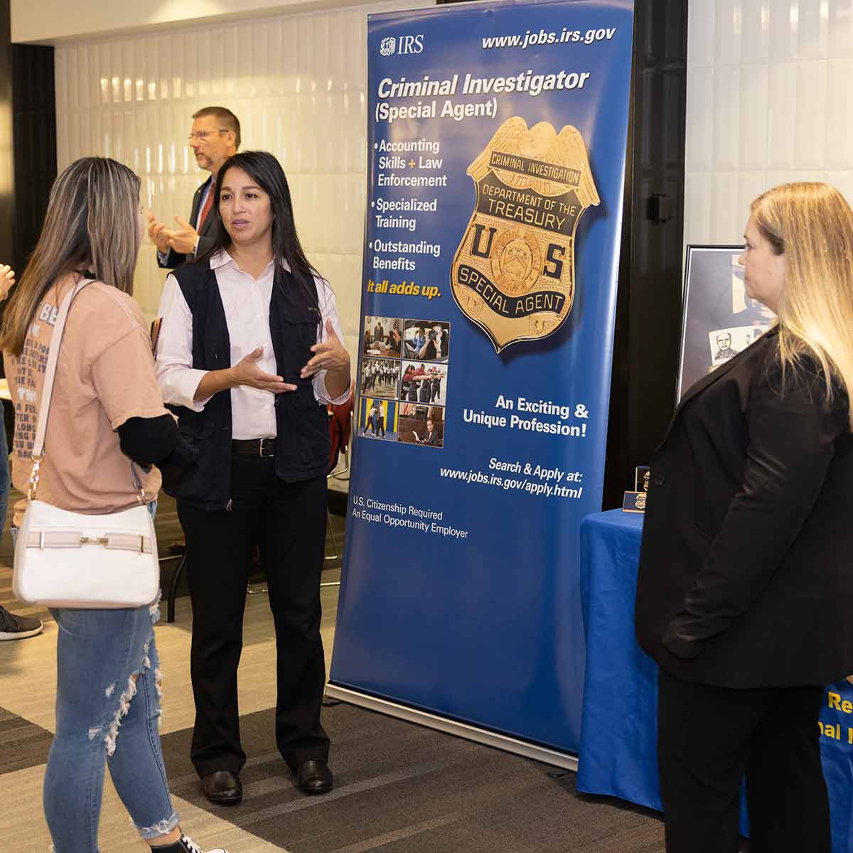 An employee from the IRS talks to a student about criminal justice positions during open house