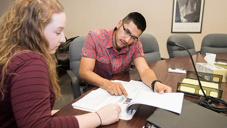 Two students reading through paperwork in a courtroom.