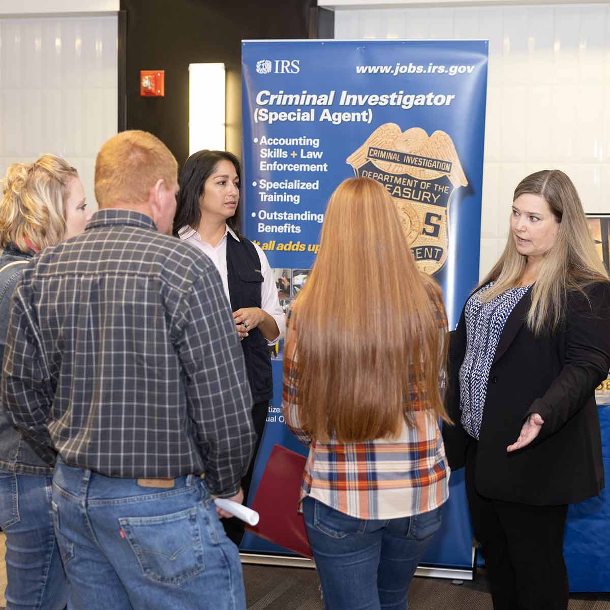 A criminology professor and employee from the IRS talking to students at an open house event.