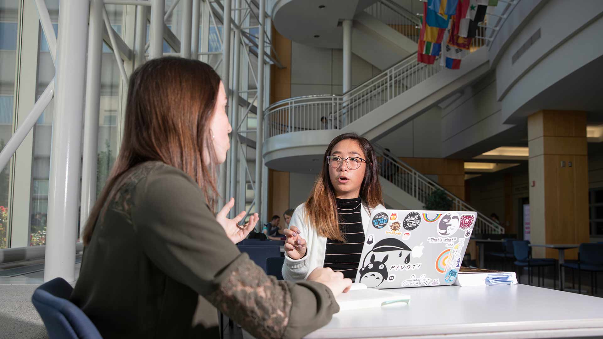 A criminology student talking to another student while seated at a table in Strong Hall.